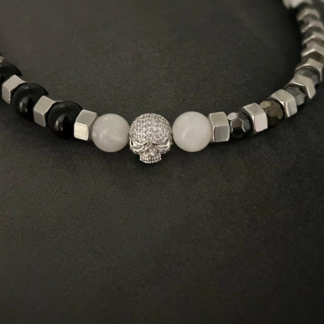 Ett Halsband i rockig design med toner i svart och silver. En berlock med döskalle i strass förser smycket med ytterligare en snygg detalj.