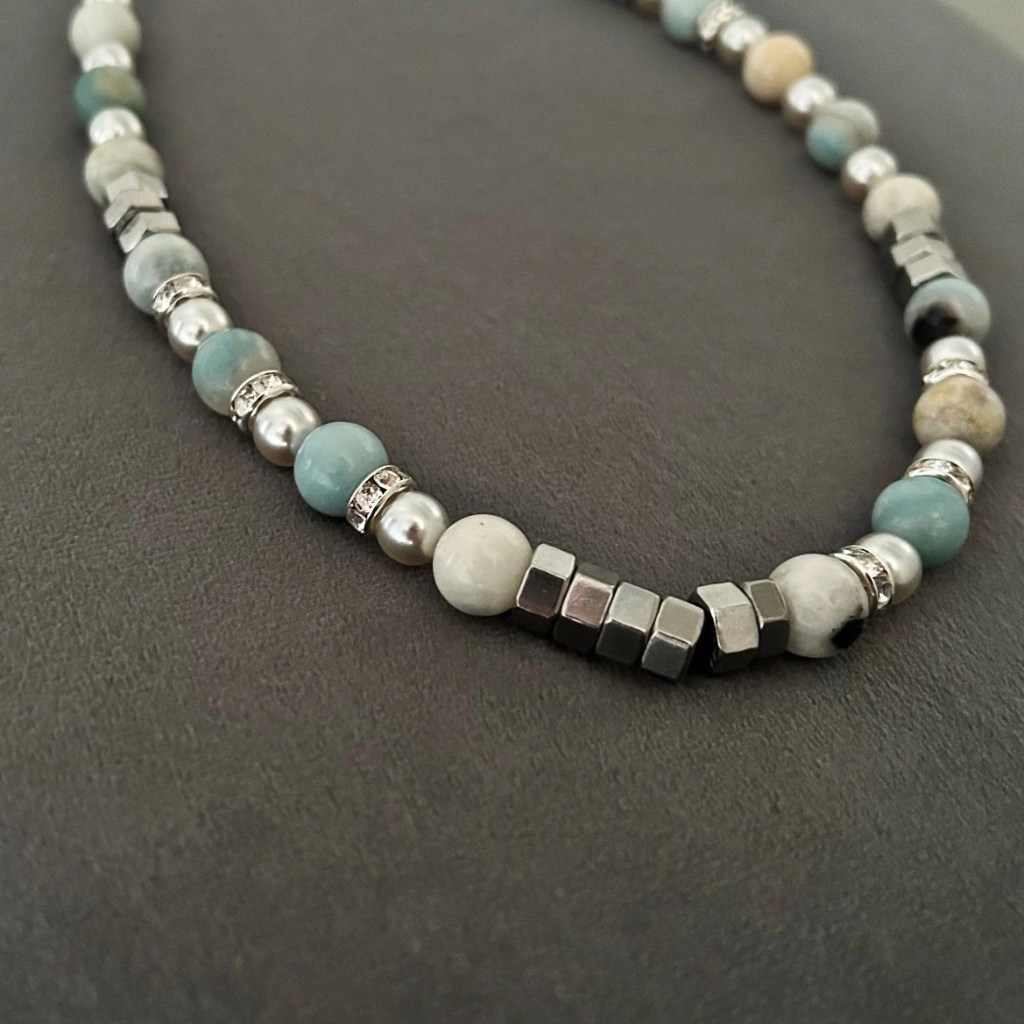 Ett mycket fint halsband försett med lava agater (ädelsten) i grå, beige, svart och turkosa skiftningar. Strass-stenar tillför halsbandet fina gnistrande detaljer.