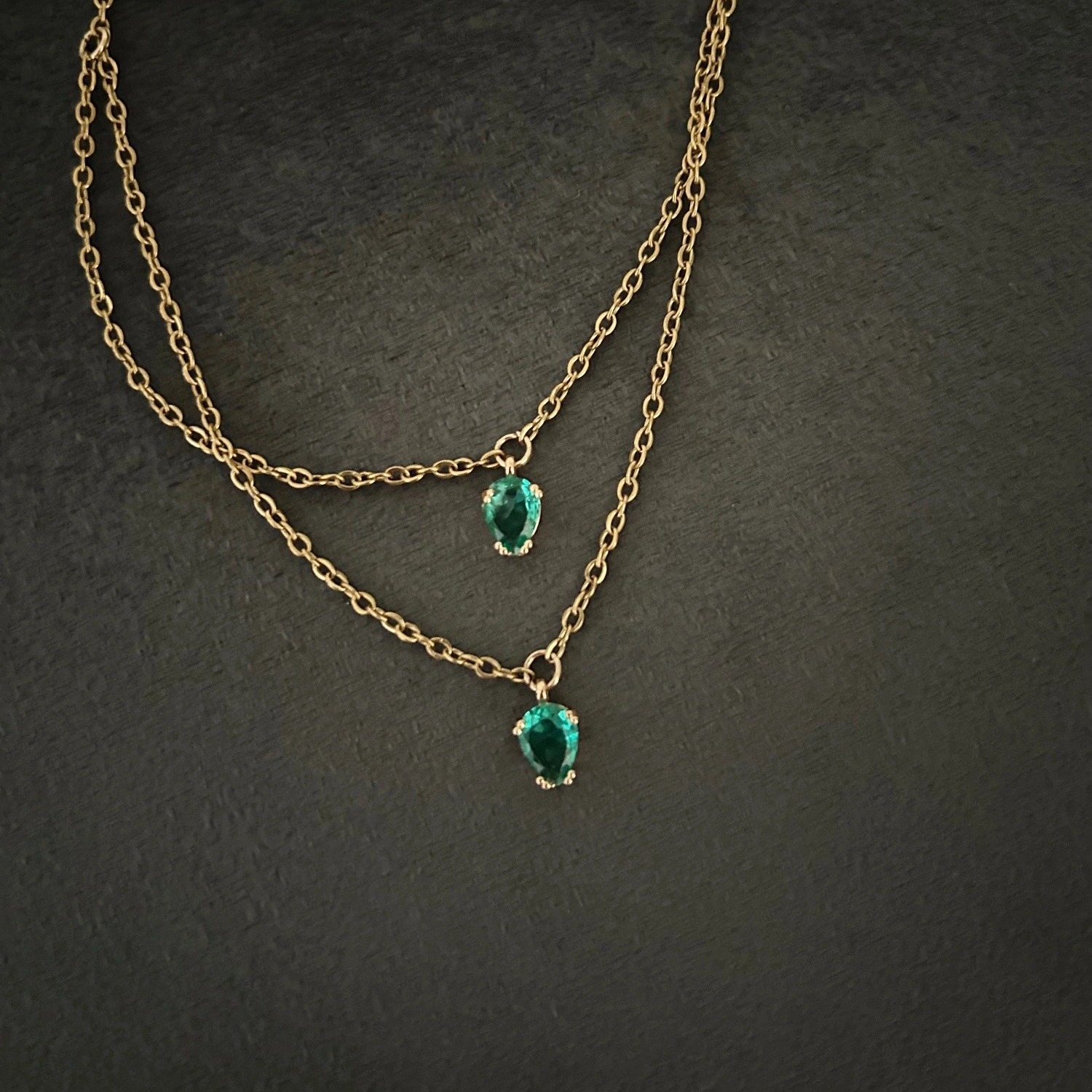 Ett prydligt halsband i smal guldkedja och dekorativ glassten i smaragdgrön nyans.