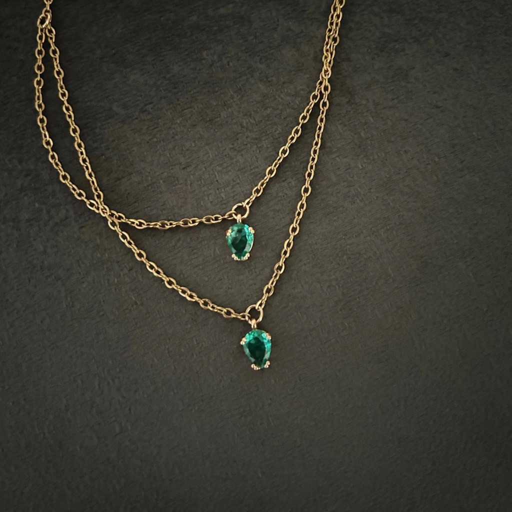 Ett prydligt halsband i smal guldkedja och dekorativ glassten i smaragdgrön nyans.