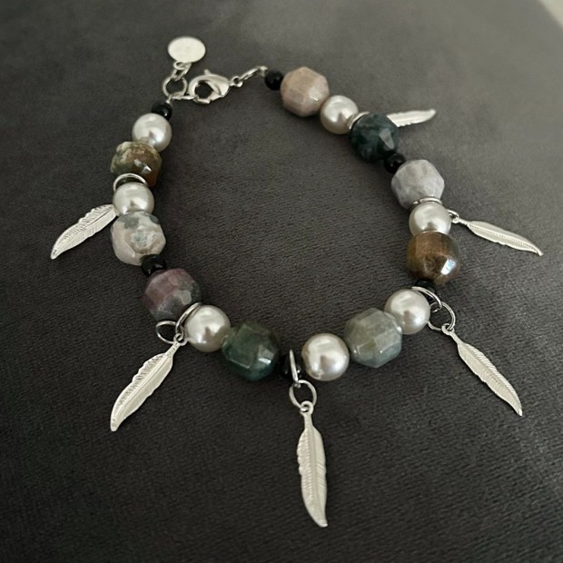 Ett dekorativt armband med Agatstenar i jordnära toner med skiftningar i grått, lila och grönt. Stenarna är något kantiga i formen. Fyra dekorativa hängen i form av fjädrar i silvriga toner tillför smycket en extra snygg detalj.