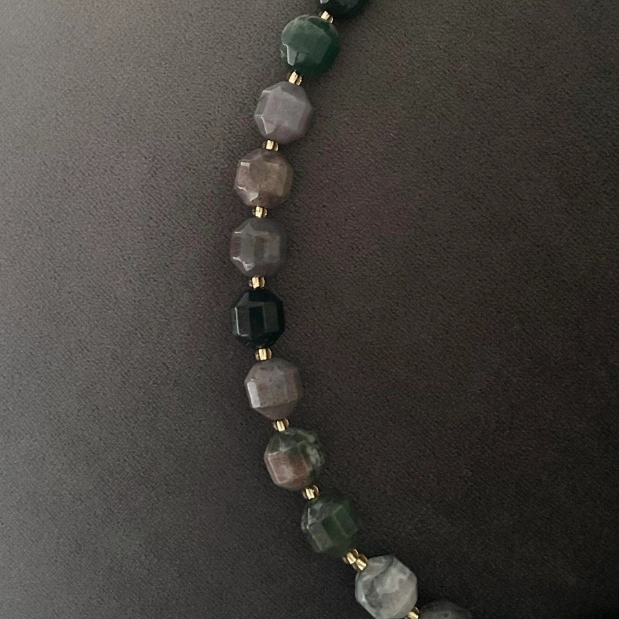 Halsband med halvädelstenar (agatsten), detta förgylls med indiska agater i en dekorativ kantig form på stenen. Smycket går i jordnära toner med vissa skiftningar i lila och grå. Halsbandet pryds också av ett hänge i moss-agat.