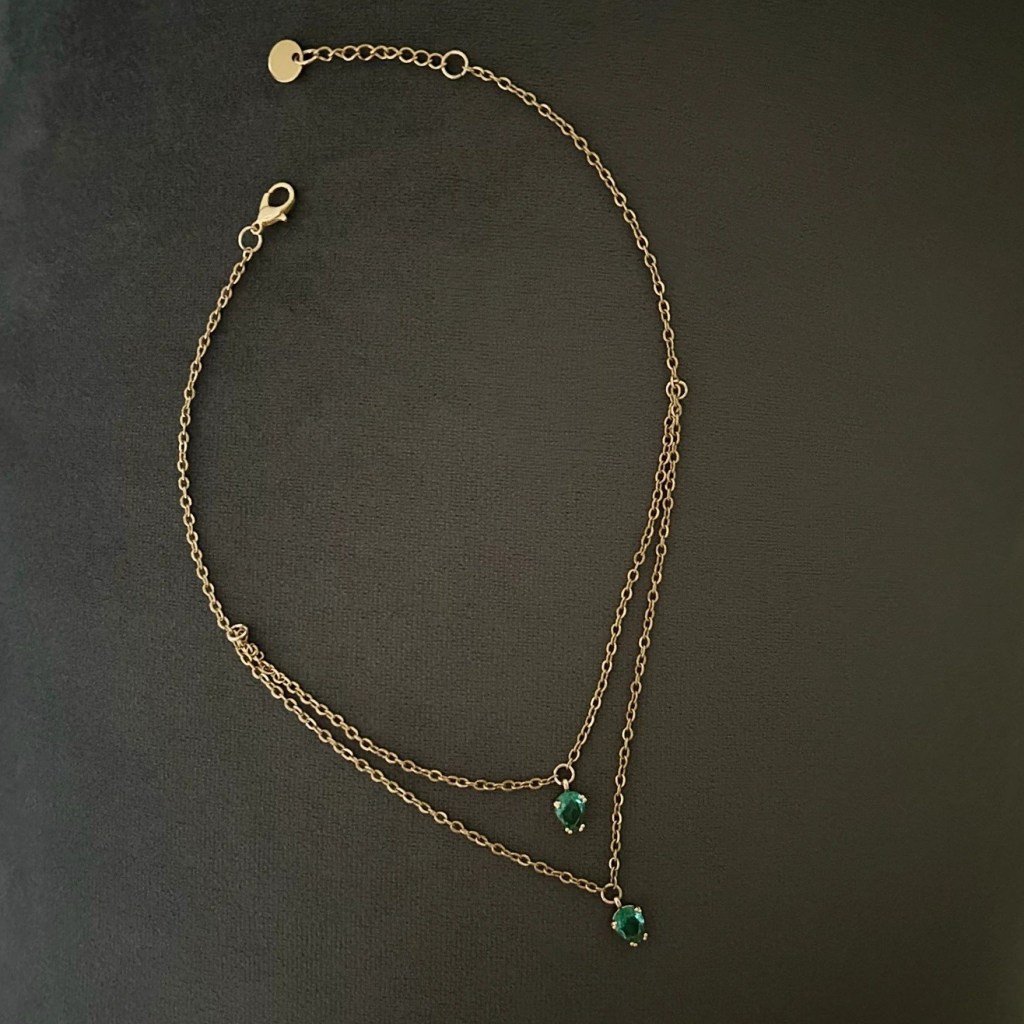 Ett prydligt halsband i smal guldkedja och dekorativ glassten i smaragdgrön nyans.