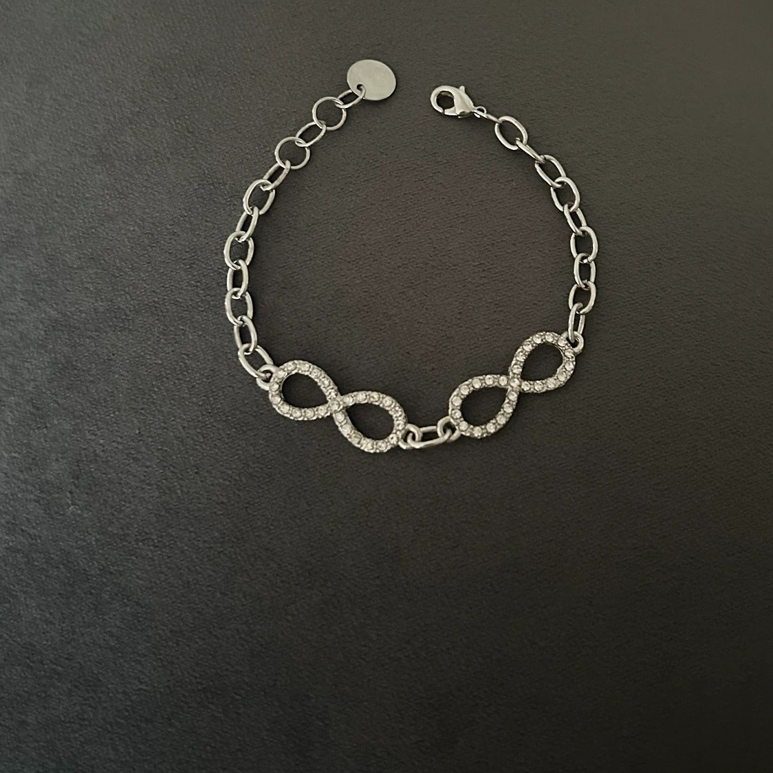 Snyggt Armband med evighets-symboler i strass som omges av kedja i silvernyans.