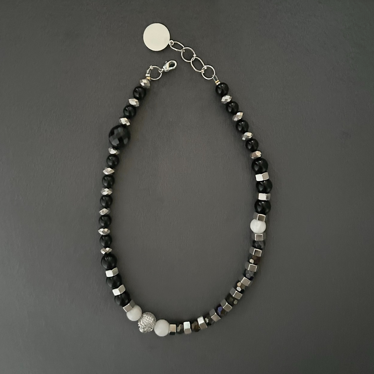 Ett Halsband i rockig design med toner i svart och silver. En berlock med döskalle i strass förser smycket med ytterligare en snygg detalj.