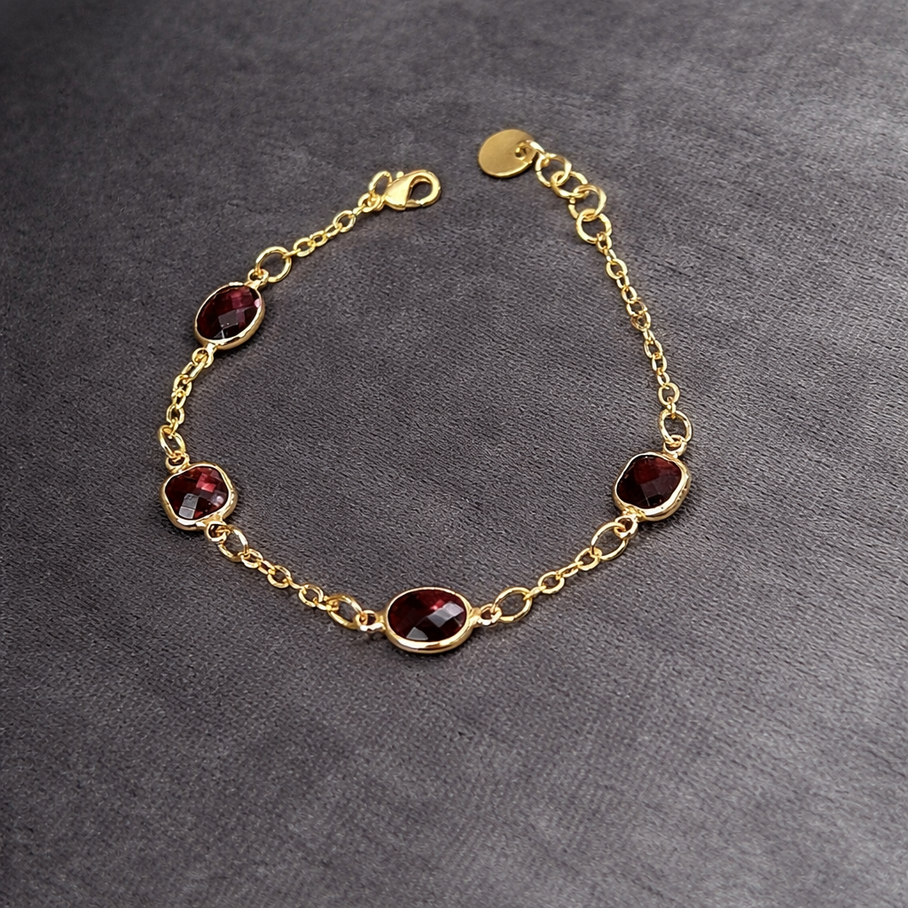 Ett smakfullt armband med smal kedja i guldfärgad nyans med fyra tindrande glasstenar i fina lila skiftningar.