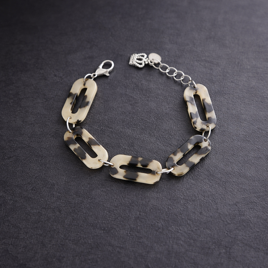 Snyggt Armband i Cellulosa med toner av leopard mönster. En berlock i form av krona förser smycket med ytterligare en snygg detalj.