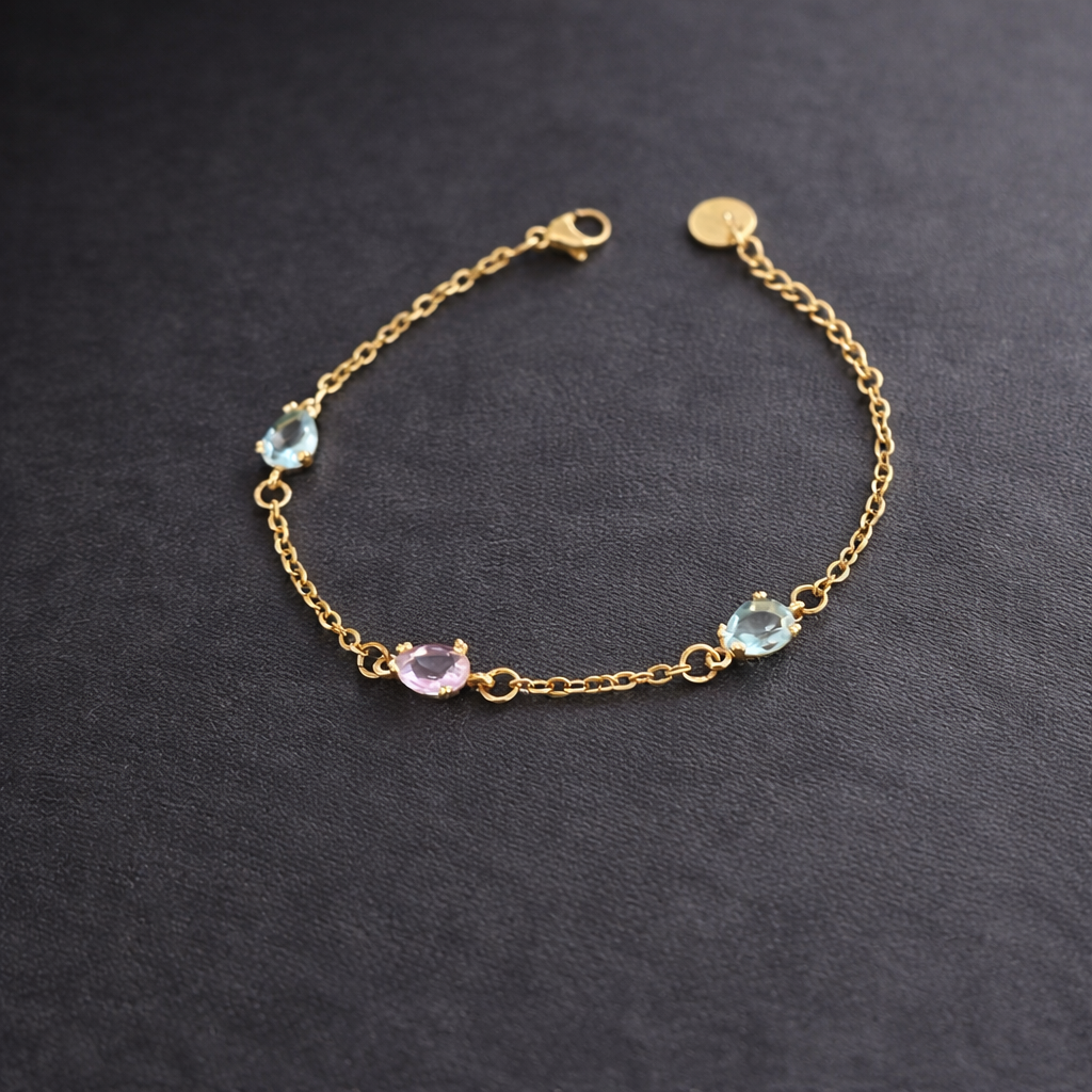 Ett fint armband i smal guldkedja som förses med dekorativa glasstenar i rosa och havsblå nyans.