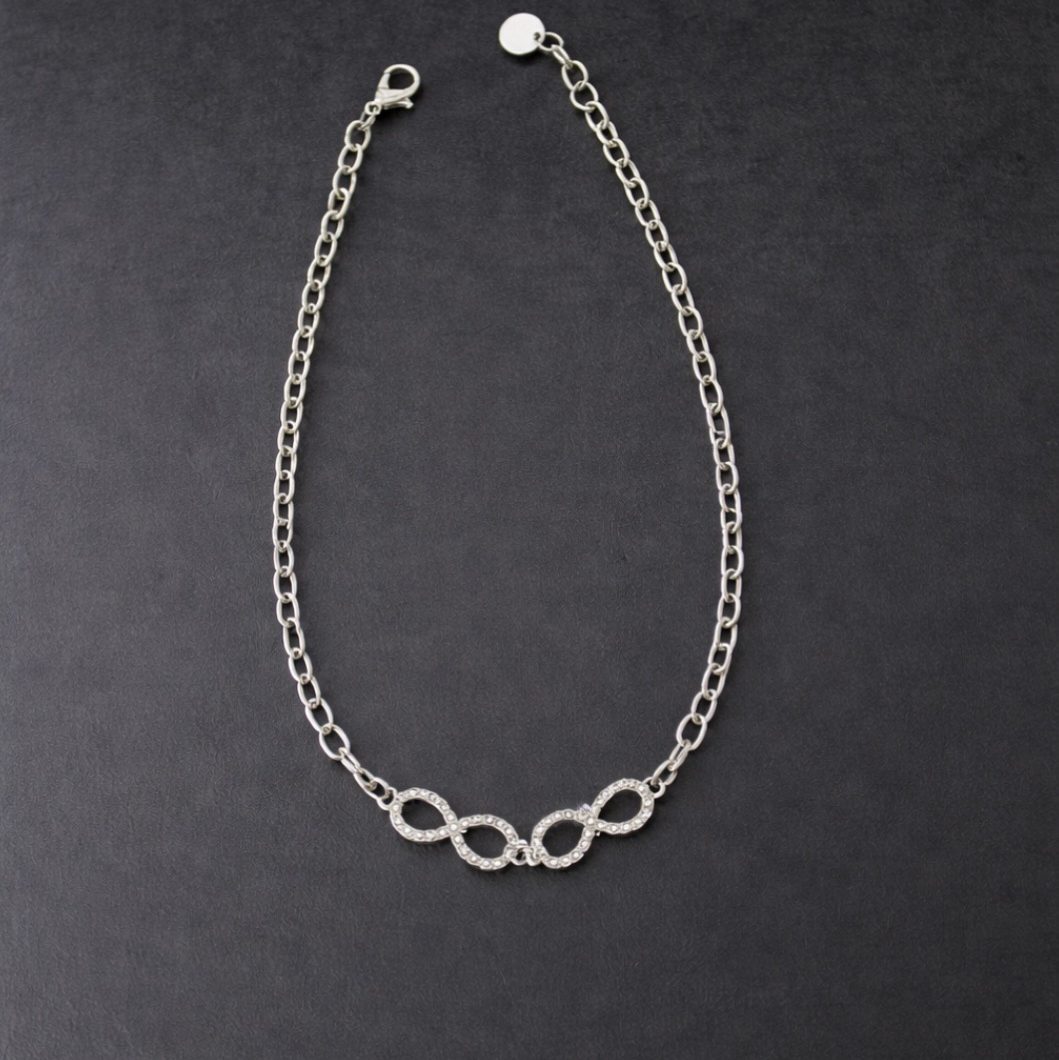 Snyggt Halsband med evighets-symboler i strass som omges av kedja i silvernyans.